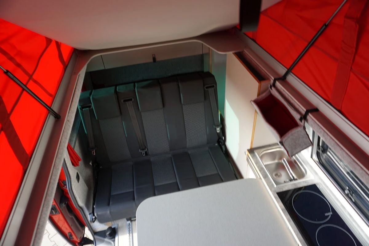 VW T6.1 in Kirschrot, Blick von oben auf Sitzbank, Küchenzeile und rotes Aufstelldach