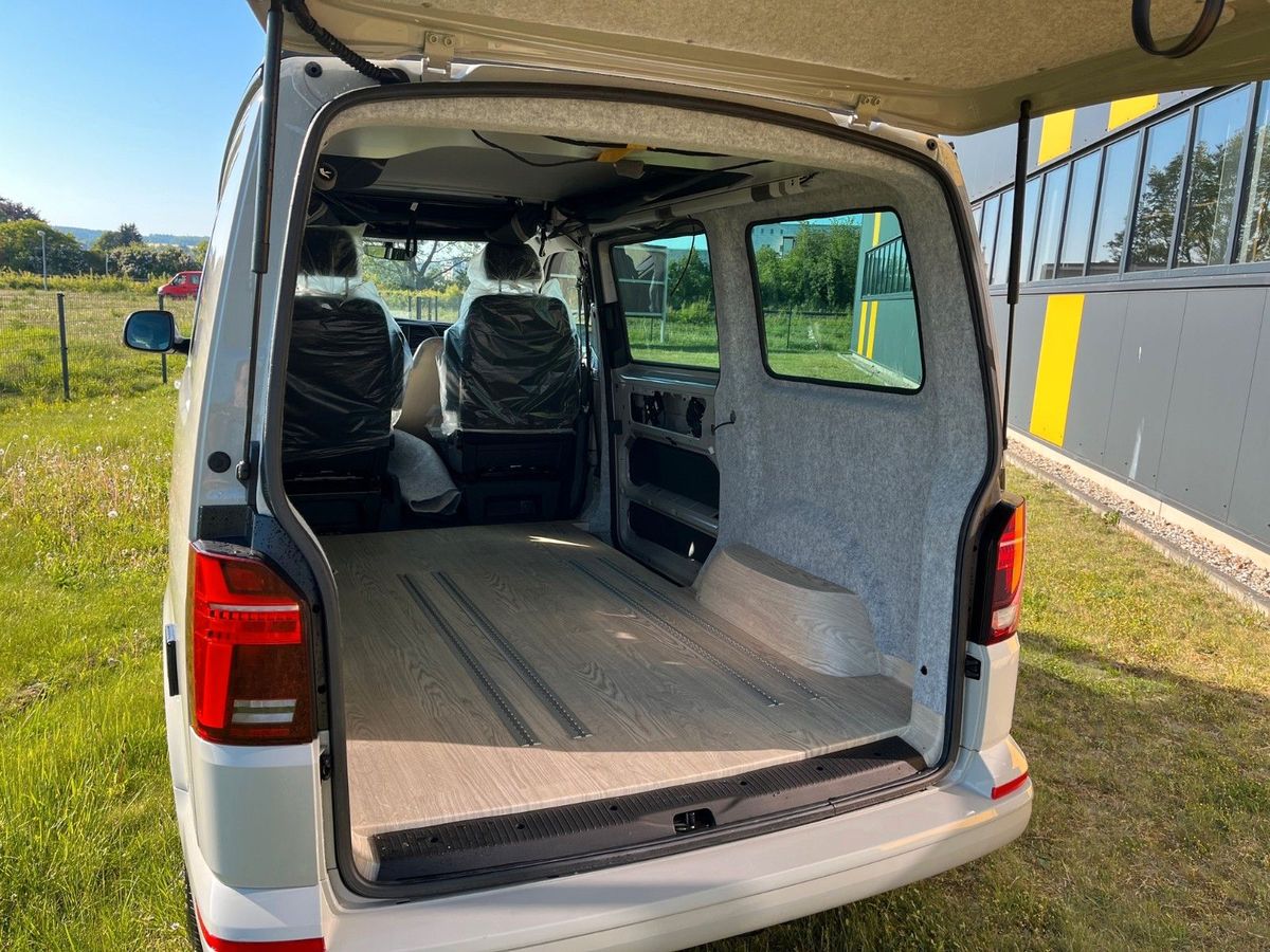 VW T6.1 in Hellrot/Ascotgrau, Blick durch die Heckklappe in den leeren Laderaum