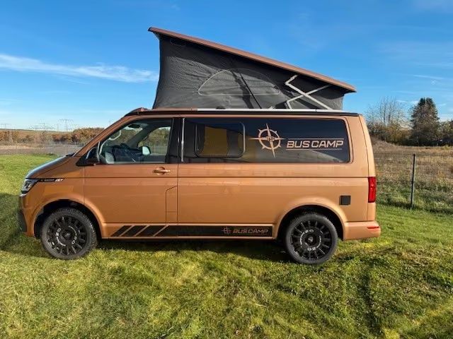 CWT 39: VW T6.1 in Copper Bronze, Seitenansicht mit geöffnetem Aufstelldach auf einer Wiese